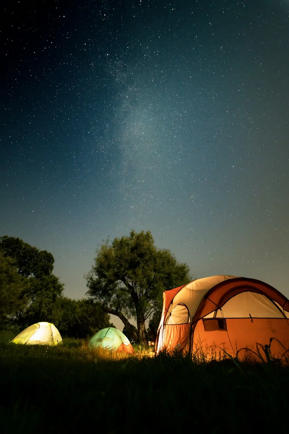 Tenda menyala di bawah langit malam penuh bintang