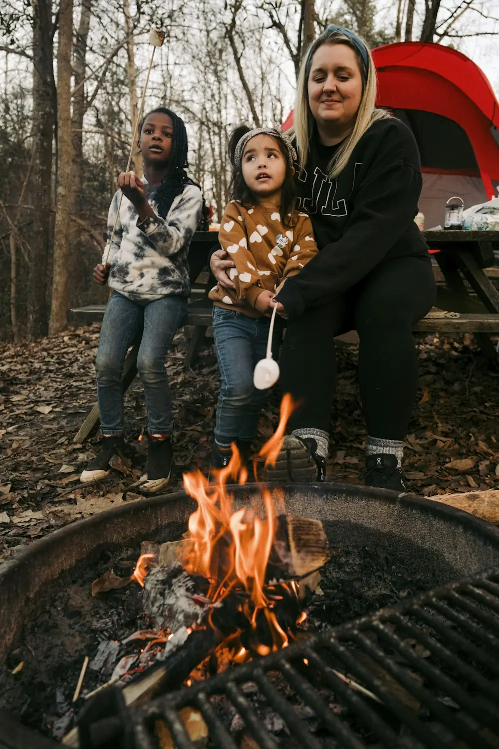 Ibu dan dua anak memanggang marshmallow di api unggun